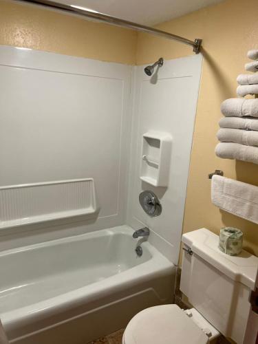 a bathroom with a white tub and a toilet and towels at Travelers Lodge Beatrice in Beatrice