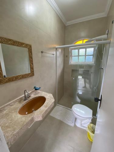 a bathroom with a sink and a toilet and a mirror at Dani Hotel in Boicucanga