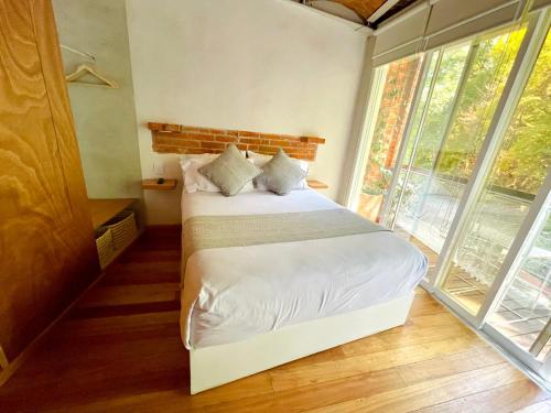 a bedroom with a bed with white sheets and windows at Sisao Hotel-Café in Cuernavaca