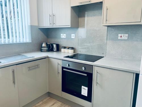 a kitchen with white cabinets and a stove top oven at Comfortable 3 bed residential home in Sheffield in Sheffield