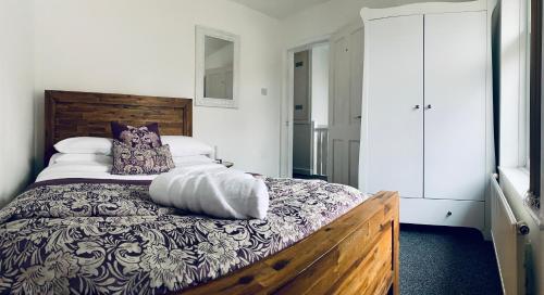 a bedroom with a bed with a wooden headboard and pillows at Comfortable 3 bed residential home in Sheffield in Sheffield