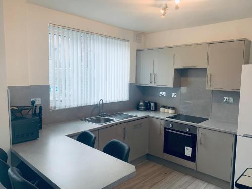 a kitchen with white cabinets and a sink and a counter at Comfortable 3 bed residential home in Sheffield in Sheffield