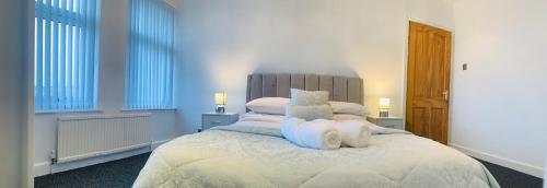 a bedroom with a large bed with white sheets and pillows at Comfortable 3 bed residential home in Sheffield in Sheffield