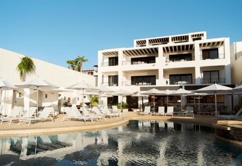 a hotel with chairs and umbrellas next to a swimming pool at Beachfront Flats Los Cabos in San José del Cabo