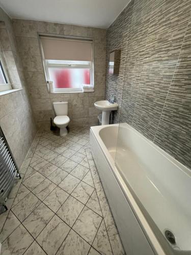 a bathroom with a tub and a toilet and a sink at Hosted By Ryan - 2 Bedroom House in Liverpool