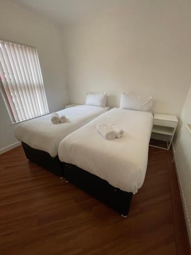 two beds in a room with white sheets and a window at Hosted By Ryan - 2 Bedroom House in Liverpool