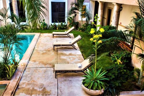 a backyard with two lounge chairs and a swimming pool at Hotel Merida in Mérida