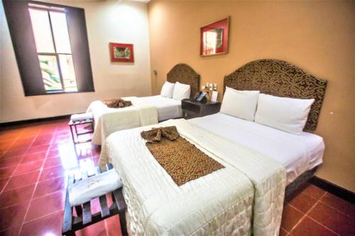 a hotel room with two beds with towels on them at Hotel Merida in Mérida