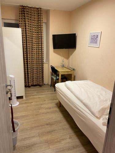 Habitación de hotel con cama y escritorio con TV. en Relax Hotel-Ludwigshafen en Ludwigshafen am Rhein