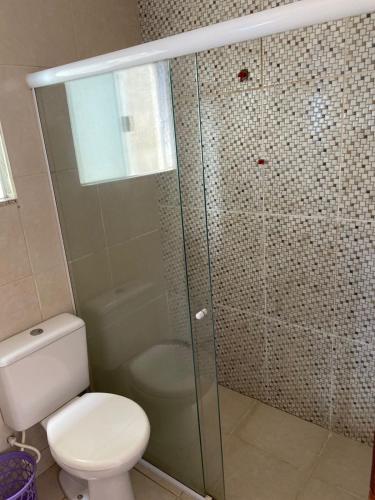 a bathroom with a toilet and a glass shower at Triplex Costazul Temporada in Rio das Ostras