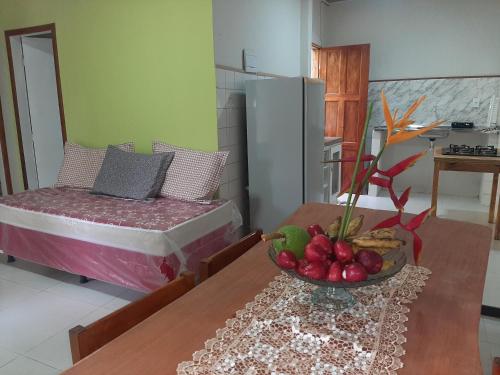 a room with a bed and a table with a bowl of fruit at Chalés vila mansos in Ilhéus
