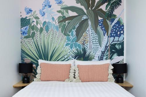 1 dormitorio con 1 cama con papel pintado tropical en Tessa's on the Beach, en Gold Coast
