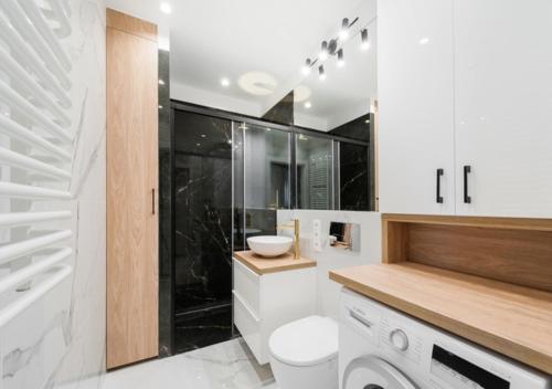 a white bathroom with a toilet and a sink at P&P Apartments in Kraków