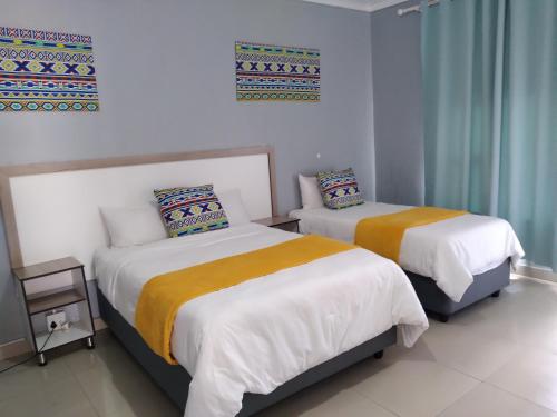 2 łóżka w pokoju z białą i pomarańczową pościelą w obiekcie Legugu Bed and Breakfast w mieście Nongoma