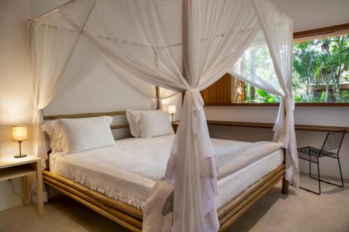 a bedroom with a canopy bed with a window at VILA 335 Trancoso in Trancoso