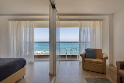 a bedroom with a bed and a view of the ocean at Jacob Resort Hadera in H̱adera
