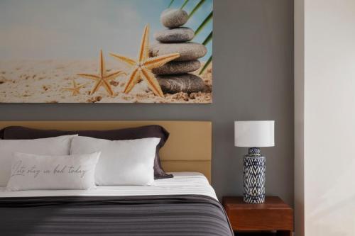 a bedroom with a bed with a picture of a beach at Jacob Resort Hadera in H̱adera