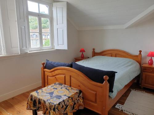 a bedroom with a wooden bed and two windows at Casa dos Cisnes - Serra da Estrela - São Paio - Gouveia - Portugal in São Paio