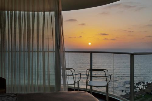 a bedroom with a view of the ocean at sunset at Jacob Resort Hadera in H̱adera
