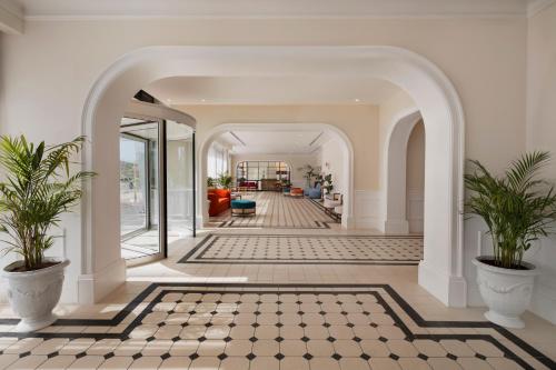 an open hallway with a checkered floor and two potted plants at Resort Hadera by Jacob Hotels in H̱adera