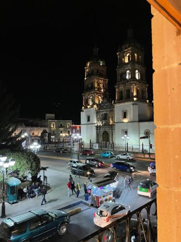 a city street with cars parked in front of two towers at La Casona Real in Durango