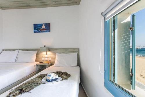 una camera con due letti e una finestra con la spiaggia di Meltemi apartment by opus ad Agios Stefanos