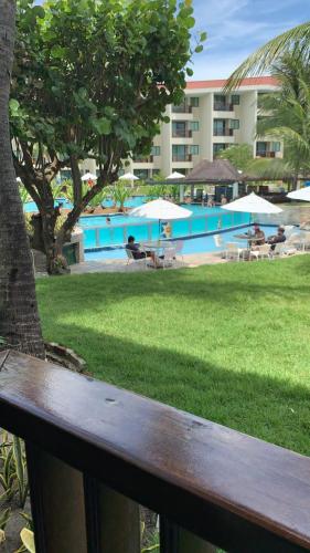 a wooden bench in front of a swimming pool at Marulhos Resort in Porto De Galinhas