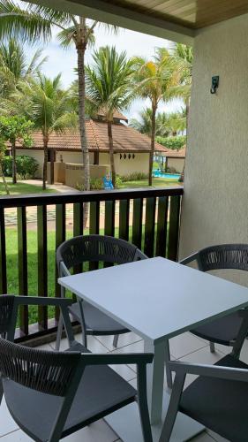 einen weißen Tisch und Stühle auf einem Balkon mit Palmen in der Unterkunft Marulhos Resort in Porto De Galinhas