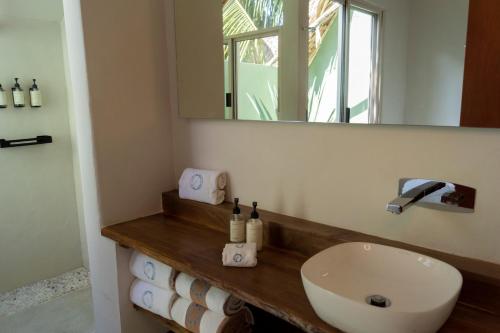 a bathroom with a sink and a mirror and towels at Hotel Circulo Bacalar in Bacalar