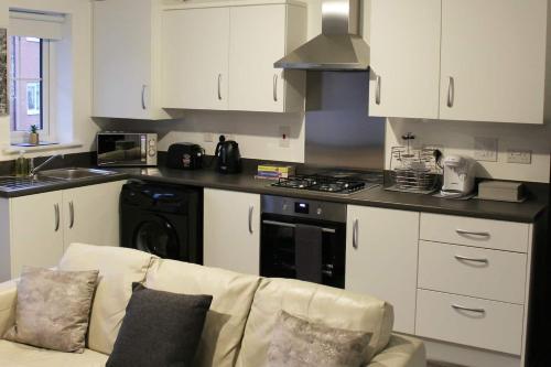 a kitchen with a couch and a stove top oven at Beautiful 1-Bed House in Peterborough in Peterborough