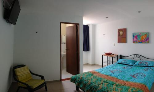 1 dormitorio con cama, silla y espejo en Córest Hotel B&B, en Tocancipá