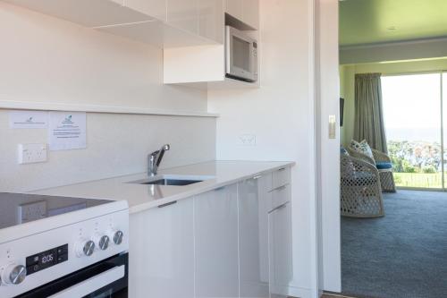a white kitchen with a sink and a microwave at Pacific Rendezvous Resort in Tutukaka