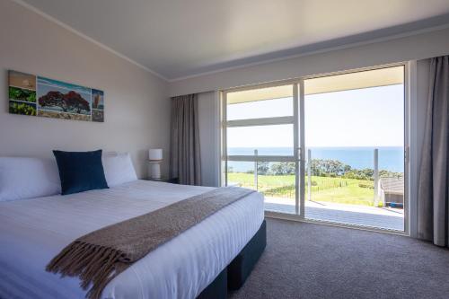 a bedroom with a large bed and a large window at Pacific Rendezvous Resort in Tutukaka