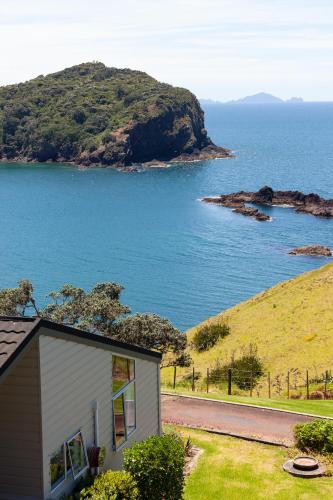 a small house on a hill next to the ocean at Pacific Rendezvous Resort in Tutukaka