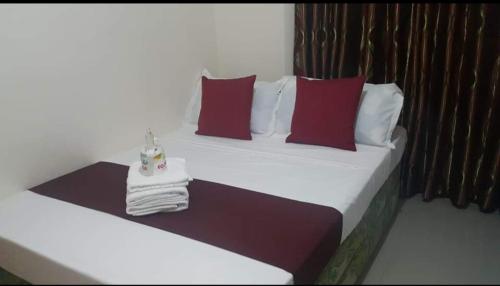 two beds with red and white pillows in a room at Serdena Homestay Fronting Cuatro Islas in Hindang