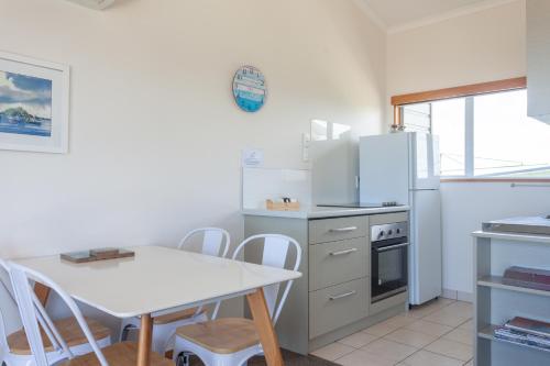 a kitchen with a white table and a white refrigerator at Pacific Rendezvous Resort in Tutukaka