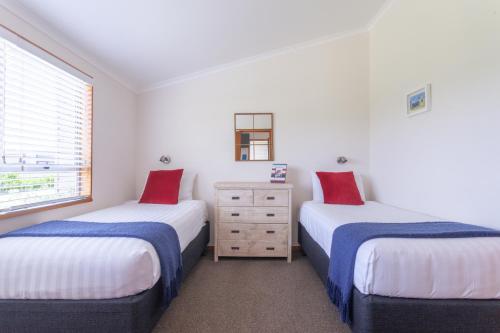 two twin beds in a room with a window at Pacific Rendezvous Resort in Tutukaka