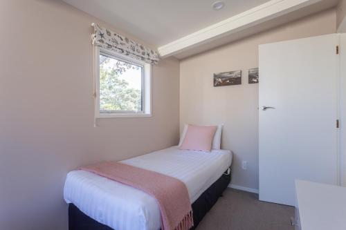 a small bedroom with a bed and a window at Pacific Rendezvous Resort in Tutukaka