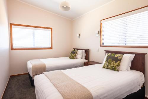 two beds in a room with two windows at Pacific Rendezvous Resort in Tutukaka