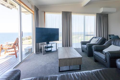 a living room with a tv and a couch and a table at Pacific Rendezvous Resort in Tutukaka