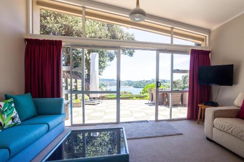 a living room with a blue couch and a large window at Pacific Rendezvous Resort in Tutukaka