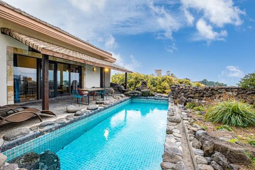 a swimming pool in front of a house at Olle Resort in Jeju