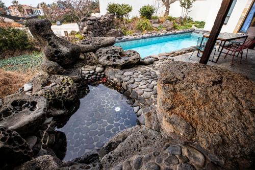 a swimming pool with a rock wall next to a yard at Olle Resort in Jeju