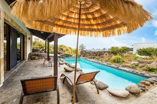 an umbrella and chairs next to a swimming pool at Olle Resort in Jeju