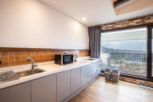 a kitchen with a sink and a microwave at Olle Resort in Jeju