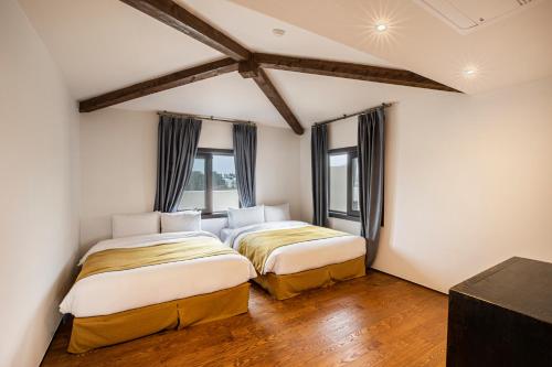 two beds in a room with two windows at Olle Resort in Jeju