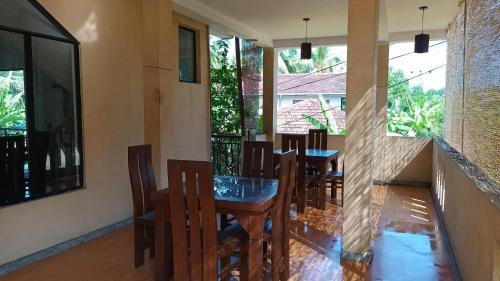 a dining room with tables and chairs and windows at My Place Guest House in Unawatuna