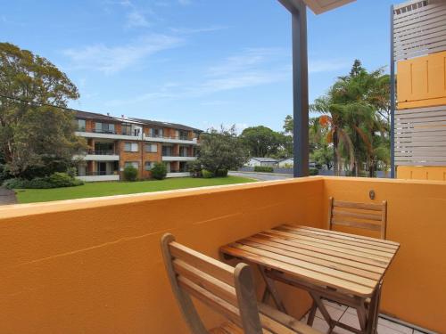 a wooden table and chair on a balcony with a building at Providence Apartment 5 in Hawks Nest