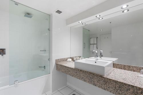 a white bathroom with a sink and a mirror at Hotel Grand Chancellor Launceston in Launceston