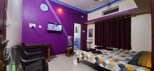 DANDELI CROCODILE EDGE HOME STAY في دانديلي: غرفة أرجوانية مع سرير وتلفزيون